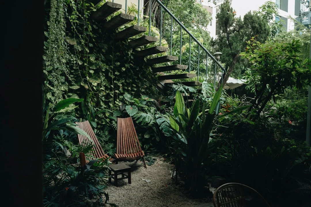 a couple of wooden chairs sitting next to a lush green wall. related to The Layered Approach to Biophilic Interior Design: How Natural Elements Improve Your Home Without Turning It Into a Jungle