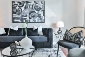 a living room with a black couch and a table with a vase with flowers on it. related to How to Decorate Your Living Room Walls Without Making These 5 Common Mistakes