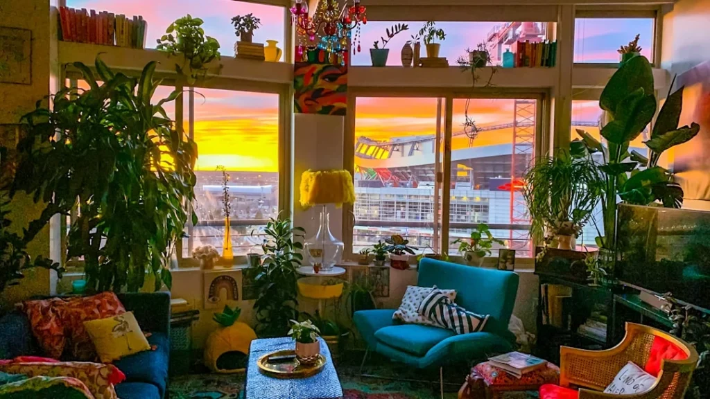 A plant-filled maximalist apartment home decor in front of Mile High Stadium in Denver during a colorful sunrise. related to Best Indoor Plants for Living Room Decor: Match Your Species to Your Space