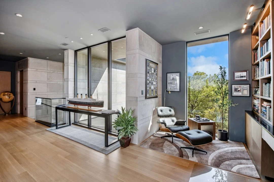 Modern living room with large windows and bookshelves. related to How to Create an Authentic Mid-Century Modern Home Without Buying Expensive Originals