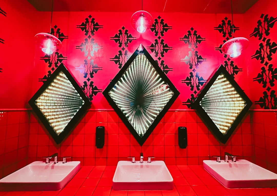 Three diamond-shaped mirrors with infinity lights above sinks.. related to Bathroom Wall Art That Survives Moisture and Matches Your Fixtures